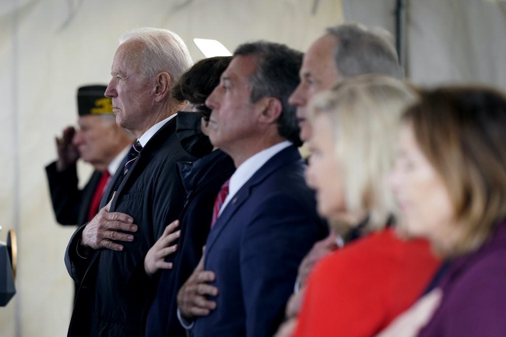 President Joe Biden, Delaware Gov. John Carney, and others stand as a rendition of the national anthem is performed