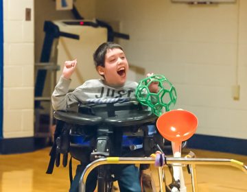 A young boy in a wheelchair having fun in gym class