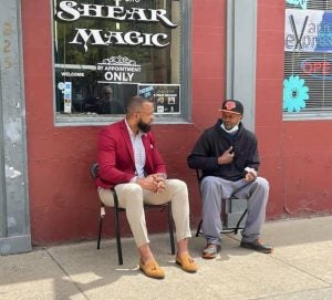 Brandon Flood speaks with a community member outside a barbershop