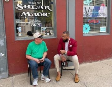 Brandon Flood speaks with a community member outside a barbershop