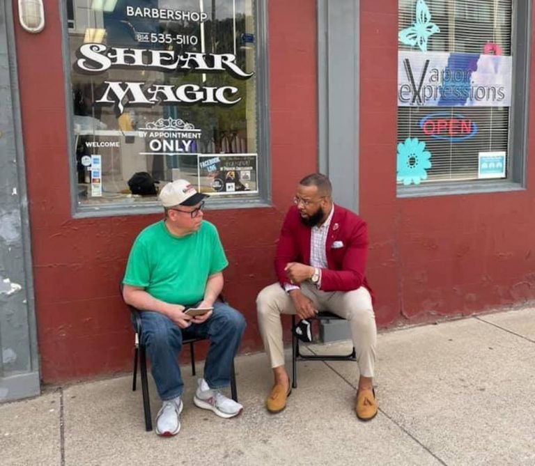 Brandon Flood speaks with a community member outside a barbershop