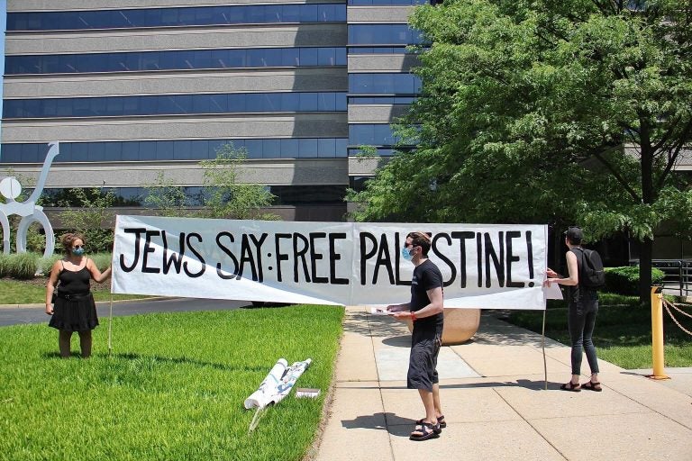 Protesters unfurl a banner outside Susquehanna Investment Group in Bala Cynwyd while others stage a sit-in inside the building. The group asked to speak with Susquehanna’s wealthy founders about their support of the displacement of Palestinians by Israel. (Emma Lee/WHYY)