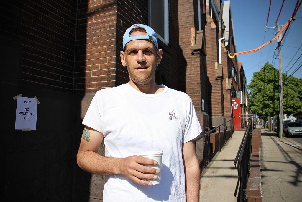 Michael Noto stands outside Snyder Avenue Congregational Church holding a cup