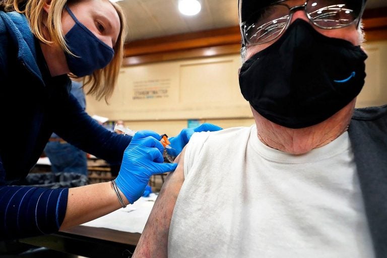 A health worker administers a COVID-19 vaccine