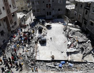 People gather near the rubble of destroyed residential building which was hit by Israeli airstrikes on Thursday in Beit Lahiya, Gaza Strip. (Adel Hana/AP)
