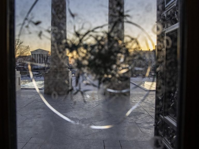 The US Capital is seen through punctured glass as National Guard secure the the grounds