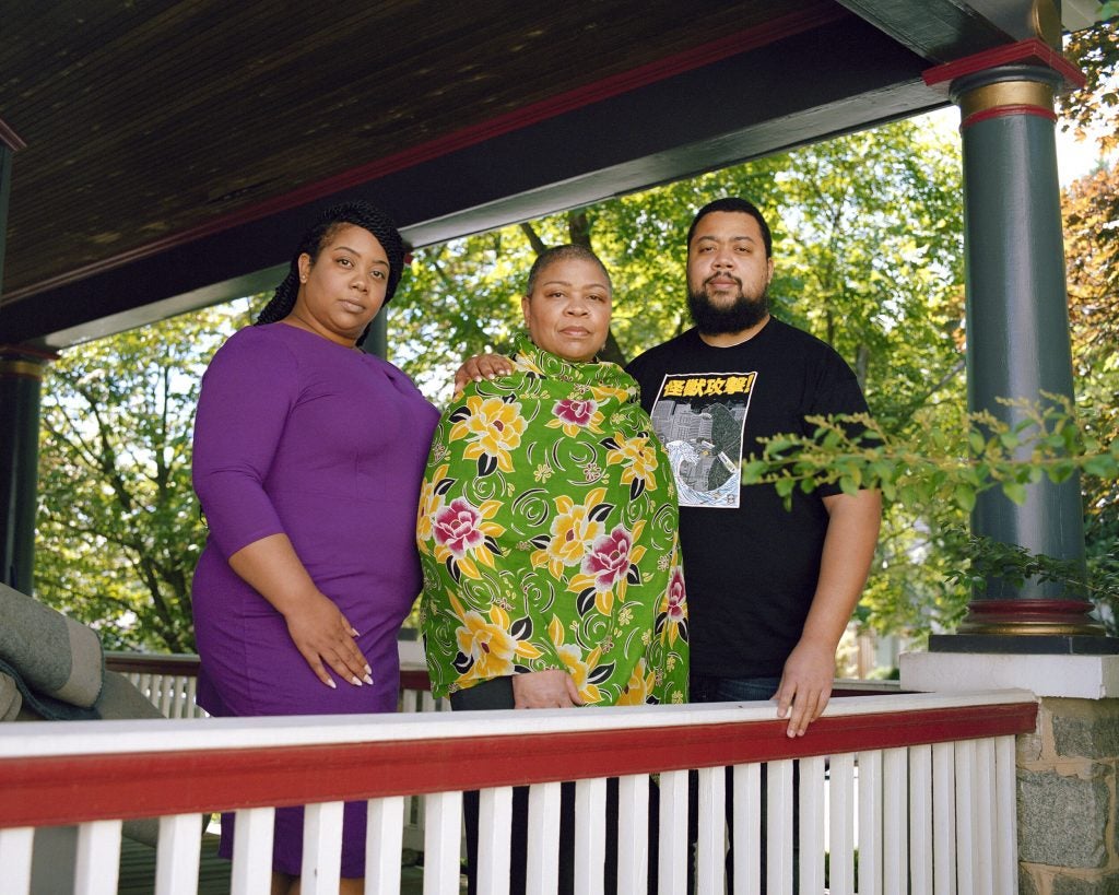 Bruner stands with her children, Portia Hurtt and Kevin Hurtt, on the front porch of their home