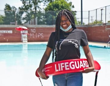 Faith Bradley stands with lifeguard equipment in front of a pool