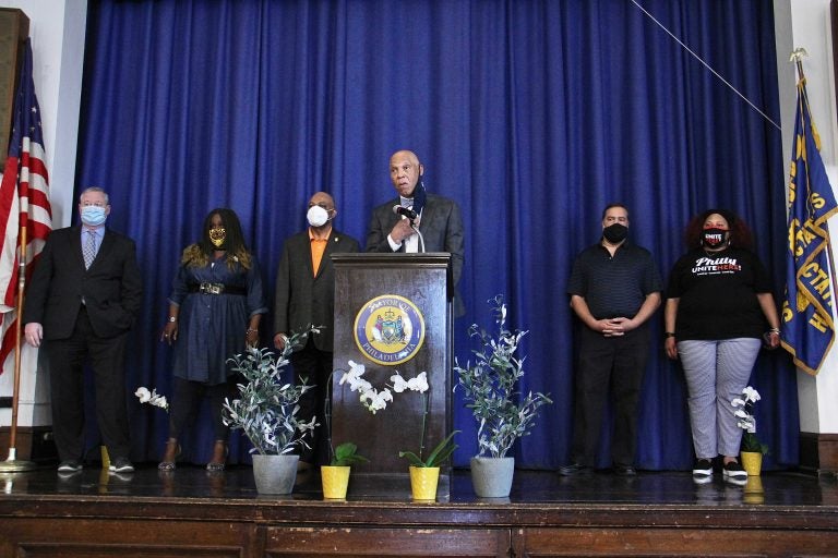 William Hite speaks from a podium, surrounded by city officials