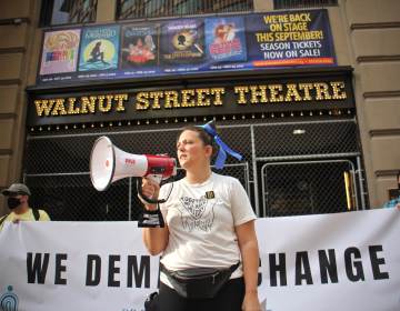 Organizer Jenna Pinchbeck reads the testimonies of those who suffered at the Walnut Street Theater to a crowd of about 80 protesters. (Emma Lee/WHYY)