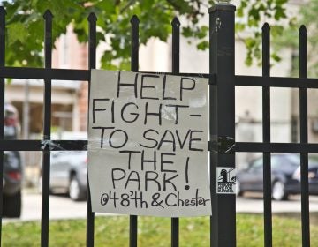 A sign on a fence reads, 