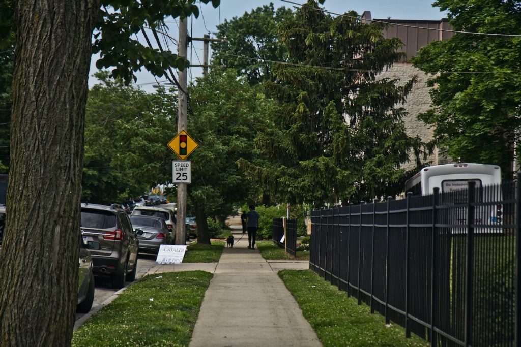 A sidewalk is pictured along a fence on a West Philly street