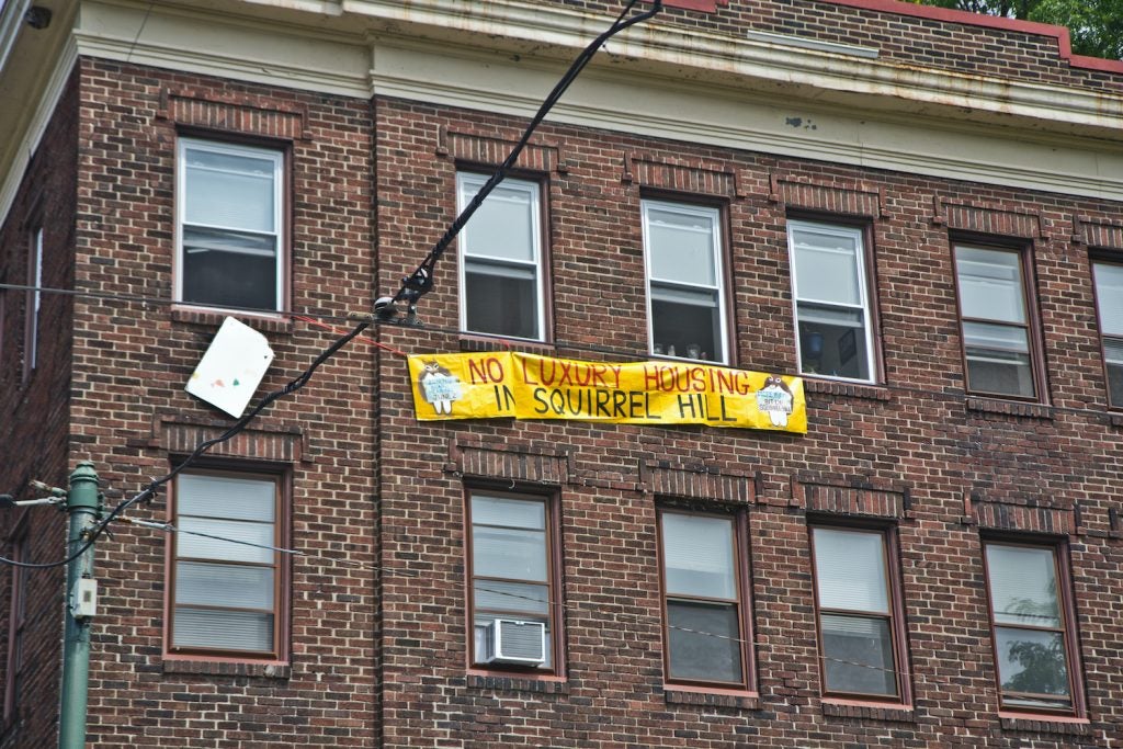 A sign hung from an apartment window reads, "No luxury housing in Squirrel Hill"