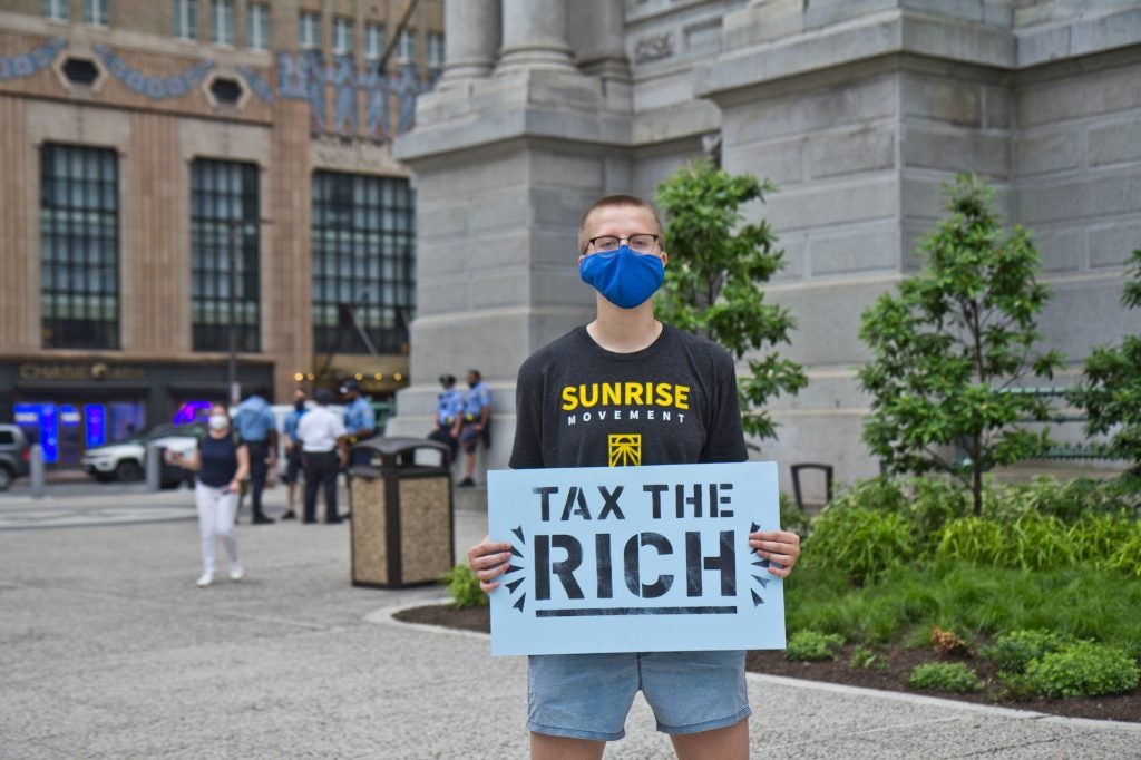 Emily Telstad holds up a sign that says, "Tax the rich."