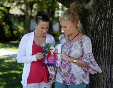 Angela Ermold, right, and her sister, Denise Gracely, hold a photo of their mother, Marian Rauenzahn, Thursday, June 17, 2021, in Fleetwood, Pa. Pandemic restrictions are falling away almost everywhere — except inside many of America’s nursing homes. “They have protected them to death,” said Gracely. (AP Photo/Matt Slocum)