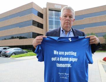 Ray Feldmann, who lives blocks away from the Capital Gazette's former office where five people were killed in a 2018 mass shooting, stands in front of the building Monday, June 21, 2021, in Annapolis, Md. He holds a shirt with a quote from Chase Cook, a staffer at the newspaper who is no longer there after taking a recent buyout, who made the comment in a tweet after the attack. Opening statements in the second phase of the gunman's trial to determine whether he is criminally responsible due to mental illness are scheduled for Tuesday, June 29. Jarrod Ramos already has pleaded guilty to all 23 counts against him. (AP Photo/Brian Witte)