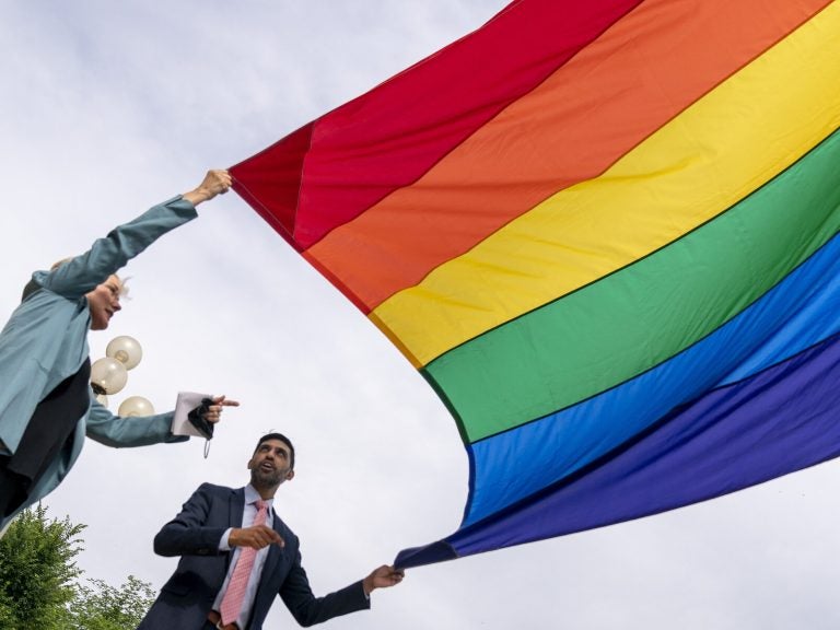 Energy Secretary Jennifer Granholm and Department of Energy Chief of Staff Tarak Shah help raise the Progress Pride Flag outside the DOE in Washington