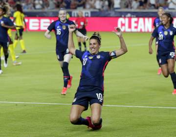 Carli Lloyd slides on astro turf during a soccer game