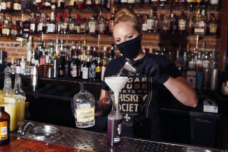 A bartender creates a cocktail in a to-go bottle