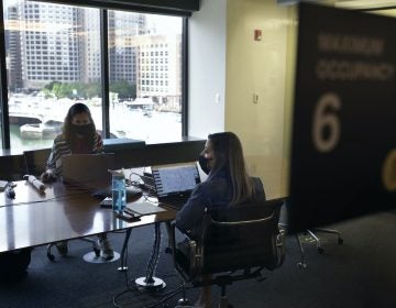 Stephanie Jones, left, and Tara Martin, right, work in a conference room while wearing face masks
