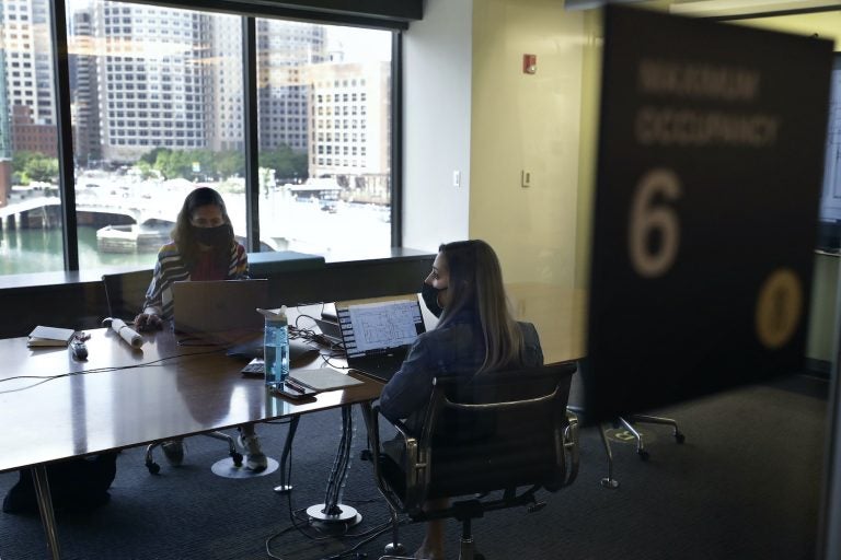 Stephanie Jones, left, and Tara Martin, right, work in a conference room while wearing face masks