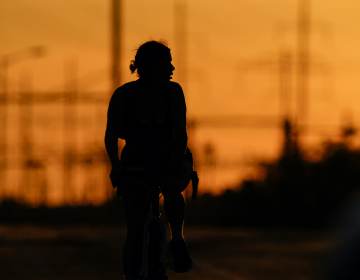 A cyclist rides in the day’s diminishing light