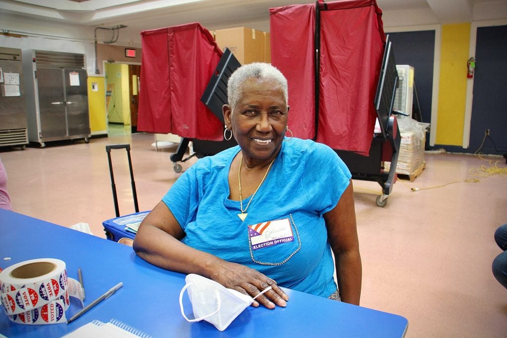 Election Official Brenda Barnes-Roman smiles while sitting at a table at a polling station