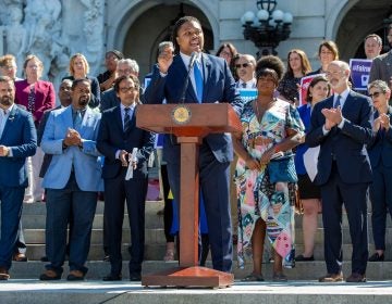 Rep. Malcolm Kenyatta speaks at a podium, with a group of lawmakers behind him