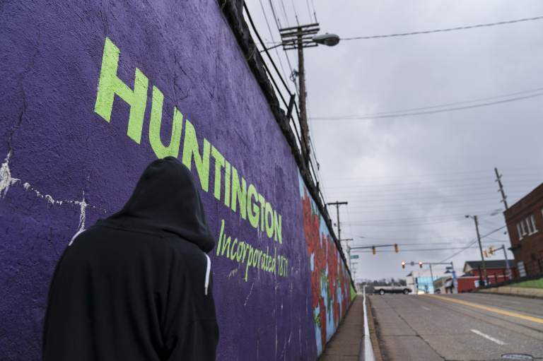 A pedestrian walks past a mural in Huntington, W.Va., Thursday, March 18, 2021. Huntington was once ground-zero for this opioid epidemic. Several years ago, they formed a team that within days visits everyone who overdoses to try to pull them back from the brink. It was a hard-fought battle, but it worked. The county's overdose rate plummeted. They wrestled down an HIV cluster. They finally felt hope. Then the pandemic arrived and it undid much of their effort: overdoses shot up again, so did HIV diagnoses. (AP Photo/David Goldman)
