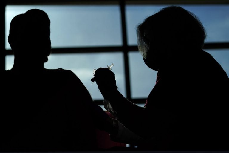 A person receives a COVID-19 vaccination from a nurse practitioner