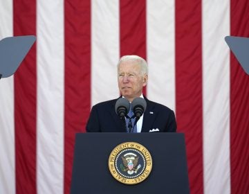 President Joe Biden speaks behind a podium, in front of an American flag