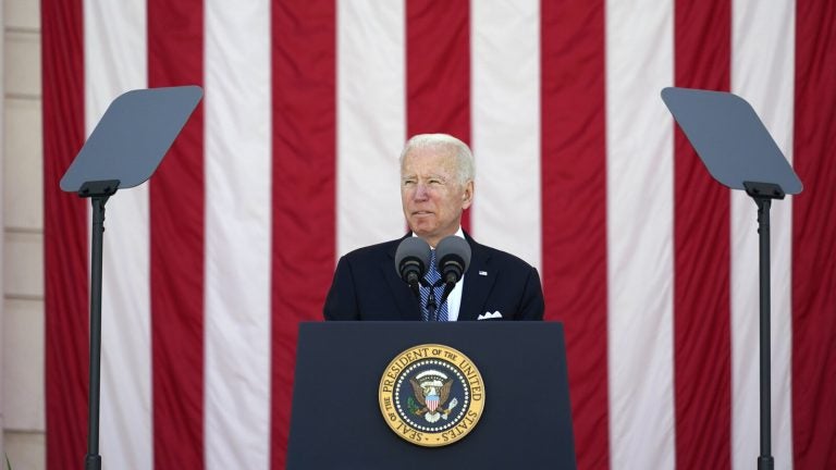President Joe Biden speaks behind a podium, in front of an American flag