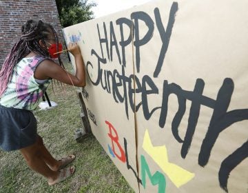 A girl paints on a poster celebrating Juneteenth