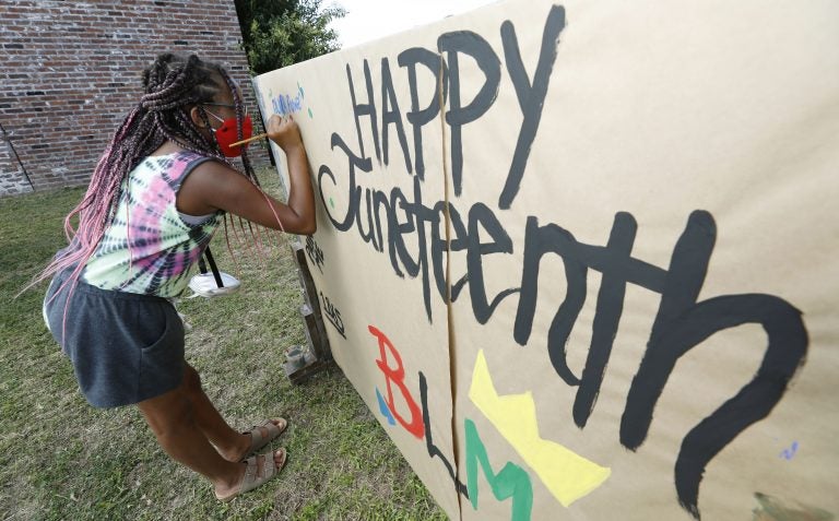 A girl paints on a poster celebrating Juneteenth