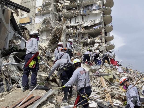 Search and rescue personnel search for survivors through the rubble at the Champlain Towers South Condo