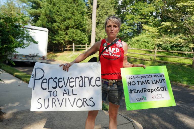 A protester outside Bill Cosby's Elkins Park, Pa., home holds a sign that reads, 