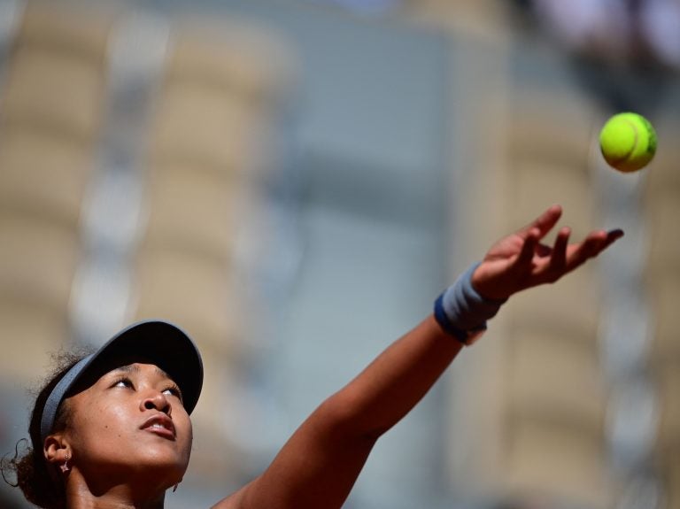 Japan's Naomi Osaka eyes the ball as she serves to Romania's Patricia Maria Tig