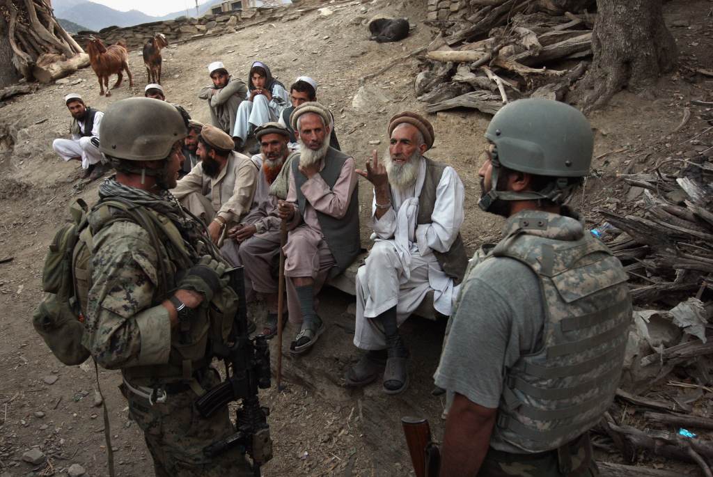 Village elders speak with a U.S. Marine (L), through an interpreter as American and Afghan forces search for weapons