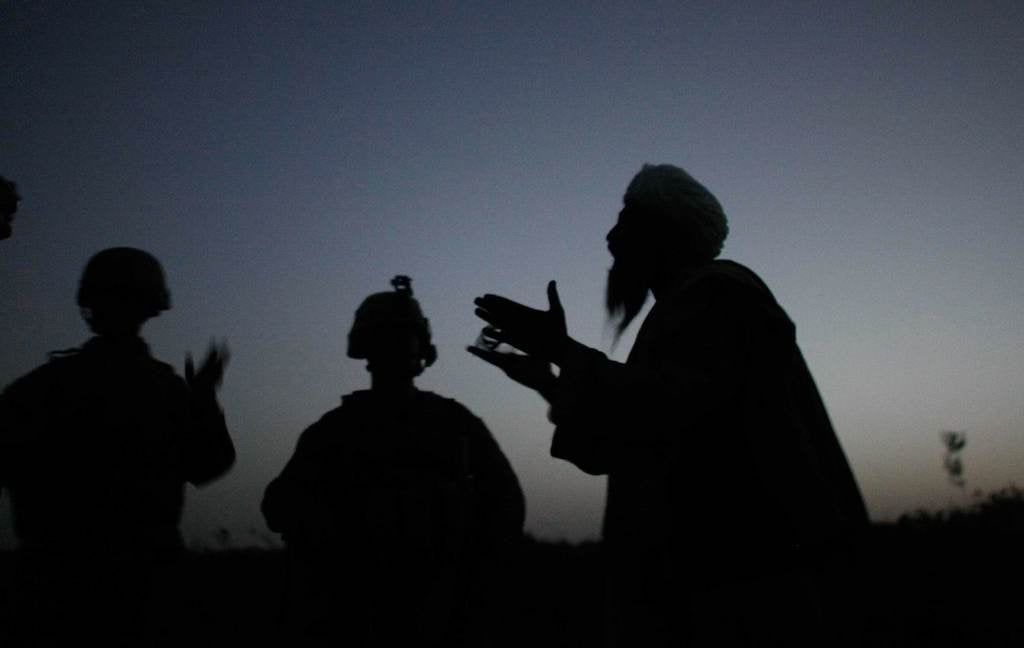 Marine Sgt. Nathan Harris speaks to an Afghan man through an interpreter after seeing suspicious activity near their base