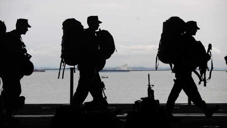 The silhouettes of military service members are pictured.