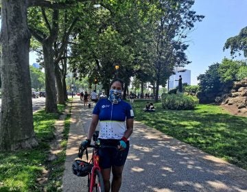 Jessica Perry stands with her bike while wearing a face mask