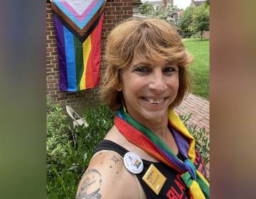 Salina Brett poses in front of an LGBTQ pride flag