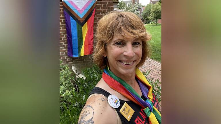 Salina Brett poses in front of an LGBTQ pride flag