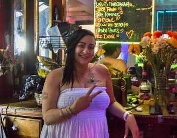 Sheila throws up a peace sign while tending bar