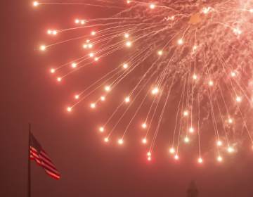JULY 4TH FIREWORKS AT PHILADELPHIA MUSEUM OF ART An American flag flutters as fireworks rain down during the July Fourth fireworks display at the Philadelphia Museum of Art. (Jonathan Wilson for WHYY)
