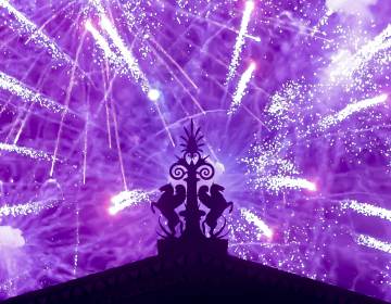 Fireworks explode in the background behind a gargoyle atop of the central portico of the Philadelphia Museum of Art. (Jonathan Wilson for WHYY)