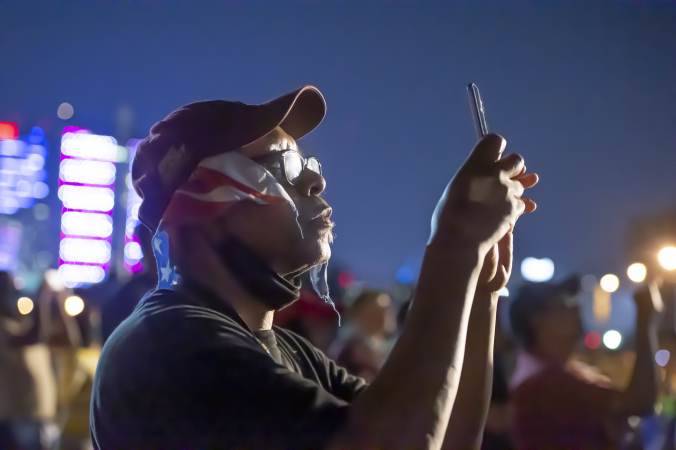 On Eakins Oval Donald Dennison using his phone records the July Fouth fireworks display. (Jonathan Wilson for WHYY)