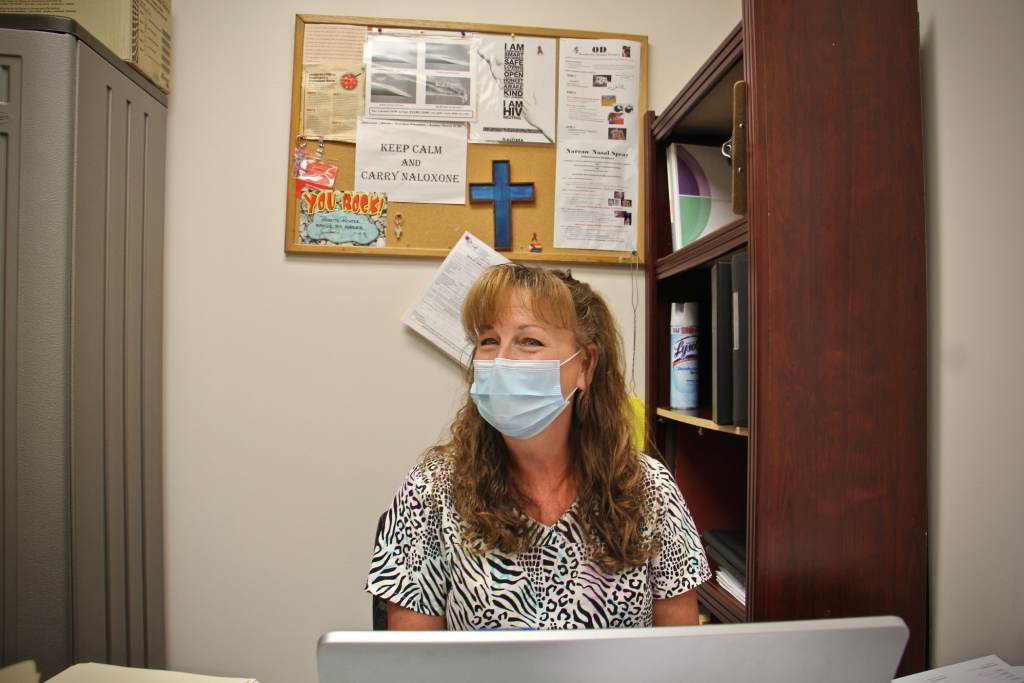 Babette Richter sits at a desk while wearing a mask