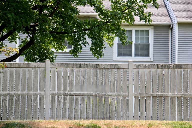 A racial slur etched into the dirt on a privacy fence at the Essex condominium complex in Mount Laurel, N.J., appears to be directed at Ron Howard, president of the homeowners association. (Emma Lee/WHYY)