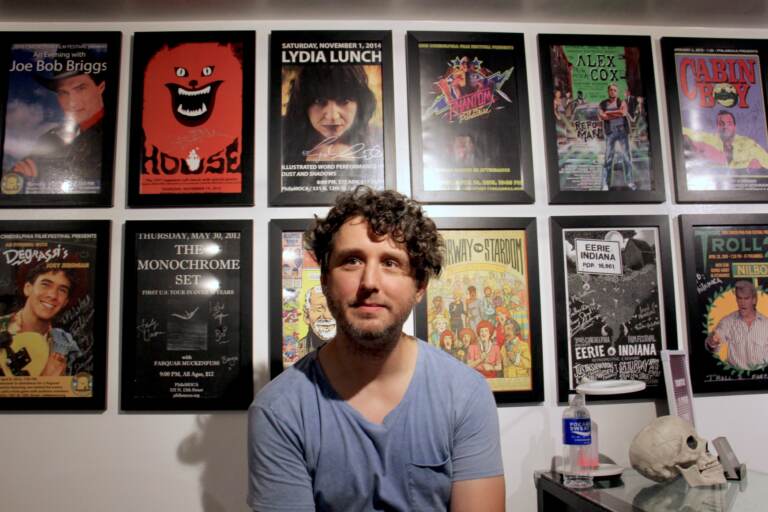 Eric Bresler sits in front of a series of posters